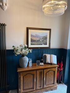 a vase of flowers on top of a wooden cabinet at Shemara rooms in Keswick
