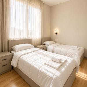 a bedroom with two beds with white sheets and a window at Hotel RADOJA in Shkodër