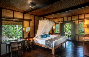 a bedroom with a bed in a room with windows at The Bali Purnati Center For The Arts in Sukawati