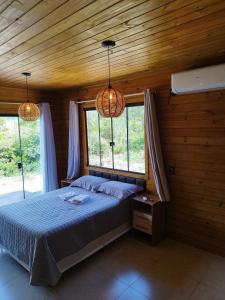 a bedroom with a bed in a wooden room with windows at Cabana Mais Natureza in Santo Amaro da Imperatriz