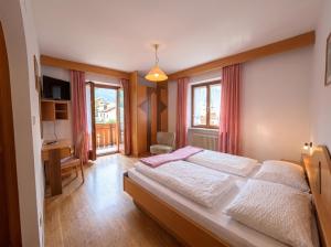 a bedroom with a large bed and a desk and window at Garni Renzler in Rasun di Sopra