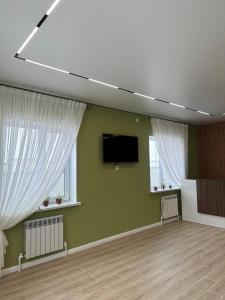 a room with a flat screen tv and two windows at Moskovskaya in Atyrau +12 photos