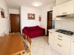 a kitchen with a red couch and a table at Anthea - Timavo apartament 1 in Lignano Sabbiadoro