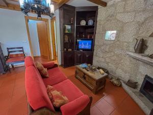 a living room with a red couch and a fireplace at Casa de Padreiro by Gerês Casas in Caniçada