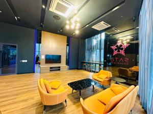 a living room with orange chairs and a television at GOLDEN Services Suites At Star KLCC in Kuala Lumpur +29 photos