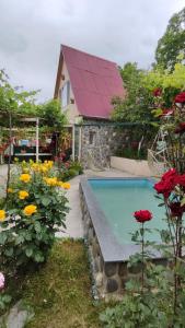 a swimming pool in a garden with flowers and a house at Friendly Cottage with small Pool in Ambrolauri