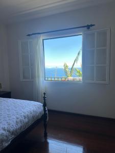 a bedroom with a window with a view of the ocean at Casa 52 in Machico