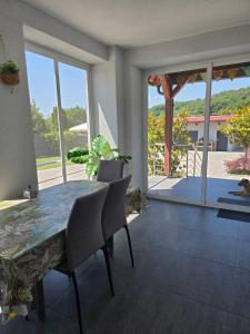 a dining room with a table and chairs and a balcony at Apartment Sunrise in Batina