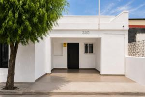 a white building with a black door and a tree at Alameda Suites & CAS - Centro Monterrey in Monterrey