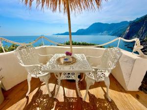 a table and chairs on a balcony with a view of the ocean at Suite Luna in Praiano
