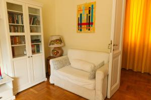 a living room with a white chair and book shelves at Borghese Magnolia Suite in Rome