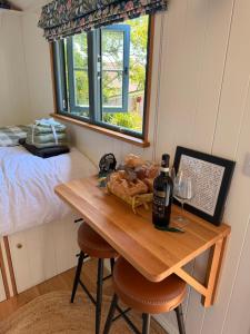 a table with a bottle of wine and a glass at Shepherds Hut in St Austell