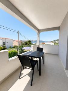 a dining room with a table and chairs on a balcony at Paulina Harmony Rooms in Seget Vranjica