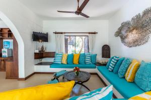 a living room with blue and yellow pillows at Watano Beach House Diani in Diani Beach