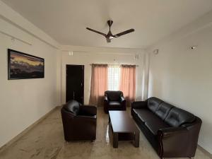 a living room with black leather furniture and a ceiling fan at KwaChen Stays in Panchanai