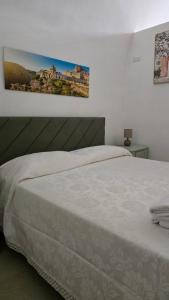 a bedroom with a white bed with a picture on the wall at Casa Alba in Bernalda