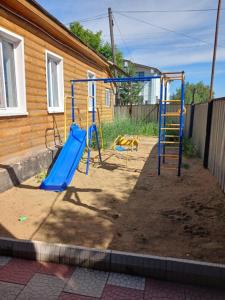 a playground with a blue slide in front of a house at Comfort Guest House in Borovoye