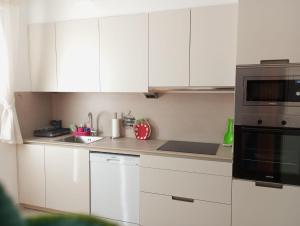 a white kitchen with white cabinets and a microwave at Apartamento A Canteira in O Grove