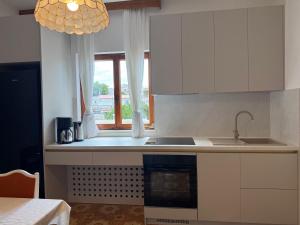 a kitchen with white cabinets and a sink and a window at Apartments Lonzor I in Selce