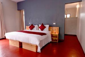 a bedroom with a large white bed with red pillows at Marera Eco Lodge in Karatu