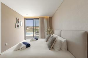 a bedroom with a bed with white pillows and a window at Quinta da Lagoeira in Caldas da Rainha