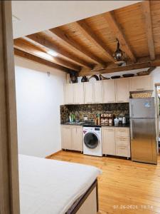 a kitchen with white cabinets and a washer and dryer at Sho Hostel in Khorugh