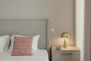 a bed with a red pillow and a lamp on a nightstand at Quinta da Lagoeira in Caldas da Rainha