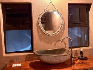 a bathroom with a stone sink and a mirror at Marudzi Sunset Lodge in Umtali