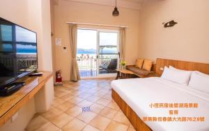 a bedroom with a bed and a television and a balcony at Little Path Kenting in Eluan