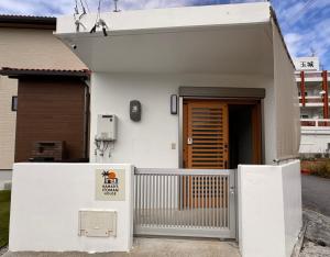 a white house with a gate and a door at HAMARs ITOMAN HOUSE - ReFaｼｬﾜｰﾍｯﾄﾞ&ﾄﾞﾗｲﾔｰ完備 - 南部観光の拠点 - 1日1組限定 in Itoman