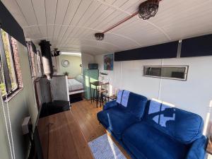 a living room with a blue couch and a bedroom at The Carriage Lorry at Tilleys Glamping in Birchington