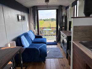 a living room with a blue couch and a kitchen at The Carriage Lorry at Tilleys Glamping in Birchington
