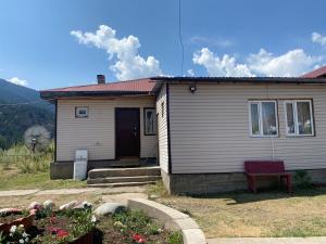 a small house with a red door in a yard at Guest hous Aibek in Kurmenty +3 photos