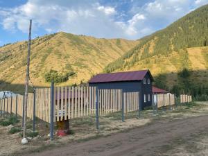 a barn with a fence next to a mountain at Guest hous Aibek in Kurmenty