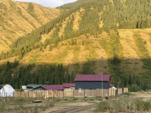 a barn in front of a mountain with a fence at Guest hous Aibek in Kurmenty