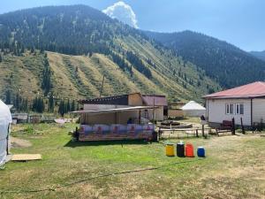 a building in a field with a mountain in the background at Guest hous Aibek in Kurmenty