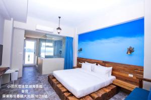 a bedroom with a large bed and a blue wall at Little Path Kenting in Eluan
