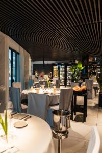 a dining room with white tables and chairs at Monaco Suites Hotel in Lignano Sabbiadoro