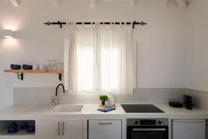 a white kitchen with a sink and a window at Vigla Villas in Volímai +189 photos