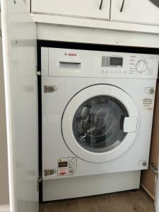 a white washing machine sitting under a counter at Northway Apartment's in Oxford