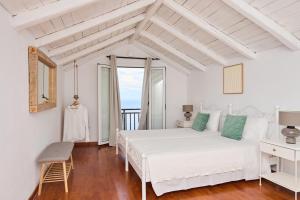 a white bedroom with a large bed and a window at Vigla Villas in Volímai