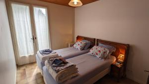 a bedroom with two beds and a large window at La maison de papy près de la plage in Barbâtre