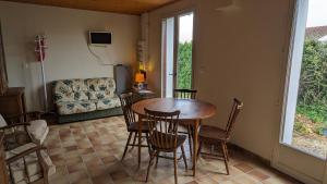 a dining room with a table and chairs and a couch at La maison de papy près de la plage in Barbâtre