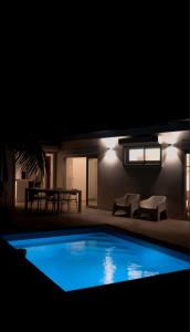 a large blue swimming pool in a yard at night at La petite villa in Le Gosier
