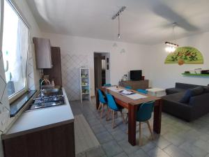 a kitchen and living room with a table and blue chairs at La vedetta di Castrocucco in Tortora