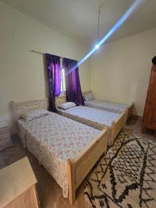 two beds in a room with a light beam at Gîte Dayet Chiker in Taza