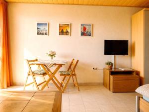 a living room with a table and chairs and a television at Panoramahuis in Sukoró