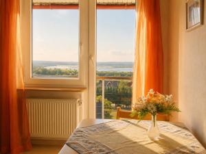 a vase of flowers on a table in front of a window at Panoramahuis in Sukoró