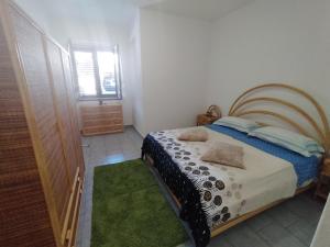a bedroom with a bed and a window and a green rug at La vedetta di Castrocucco in Tortora