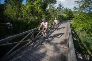 two people riding bikes on a wooden bridge at Lavanderin Apartment in Dekani